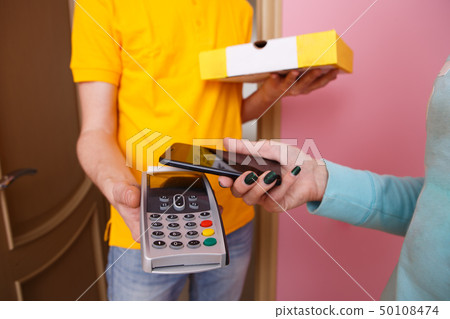 Woman pays for pizza phone to courier via pin pad Woman pays for pizza phone to courier via pin pad 50108474