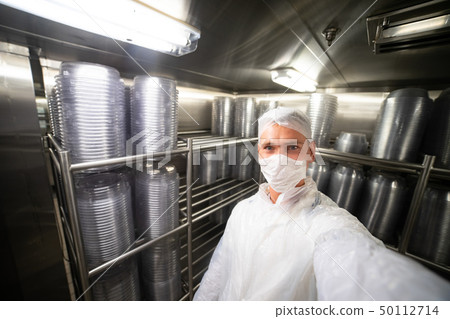 Young man taking selfie in restaurant kitchen storage room with stacks of plates, on metal shelves Young man taking selfie in restaurant kitchen storage room with stacks of plates, on metal shelves 50112714
