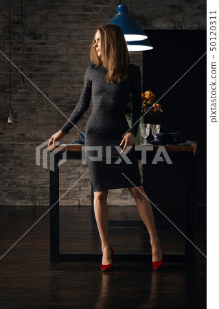 Cute girl in knitted dress standing in dining room Cute girl in knitted dress standing in dining room 50120311