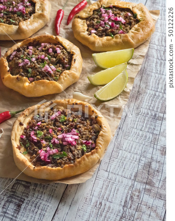 Arabian opened meat pies on white wood background. 50122226