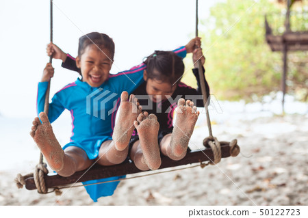 Children bare feet with sand they playing on swing 50122723