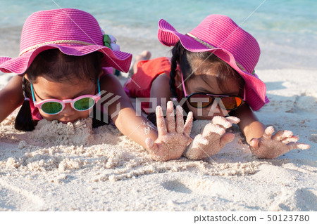 Two asian girls playing with sand on the beach 50123780
