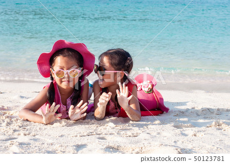 Two asian girls playing with sand on the beach 50123781