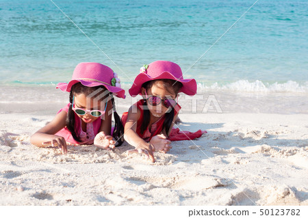 Two asian girls playing with sand on the beach 50123782