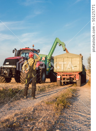 Farm woman monitoring progress of the harvest on site 50125771