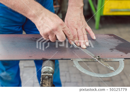 Metalworker with angle meter measuring strip of metal Metalworker with angle meter measuring strip of metal 50125779