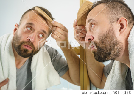 Man using comb in bathroom Man using comb in bathroom 50131338