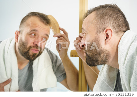 Man using comb in bathroom Man using comb in bathroom 50131339
