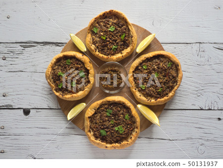 Arabic meat sfiha over a wooden table. Top view. Arabic meat sfiha over a wooden table. Top view. 50131937