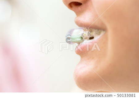 girl with braces brushing her teeth 50133081