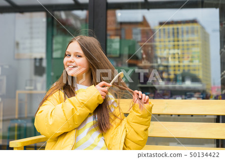 A long-haired, cheerful blonde girl combs her hair 50134422