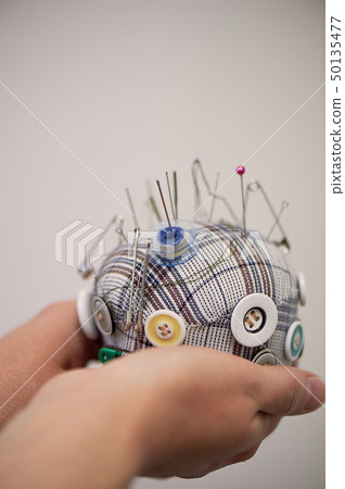 Plaid pin cushion in the hands of seamstresses.Handmade, sewing. Plaid pin cushion in the hands of seamstresses.Handmade, sewing. 50135477