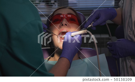 Dentist is taking care about patient's tooth using electric dental brush. Woman's portrait in dental 50138109