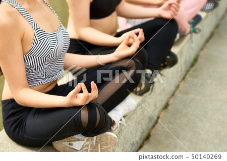 Women sitting in lotus position outdoors Women sitting in lotus position outdoors 50140269