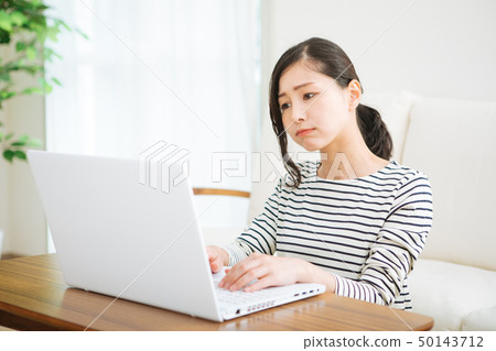 A woman who is worried while looking at a computer A woman who is worried while looking at a computer 50143712