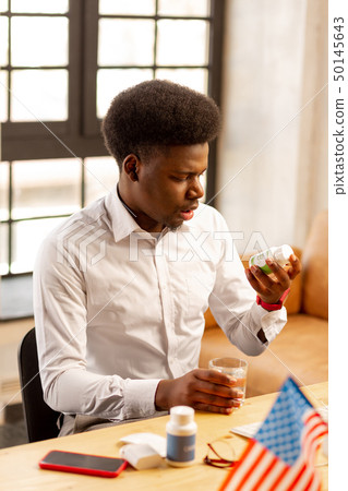 Nice handsome man looking at the bottle with pills Nice handsome man looking at the bottle with pills 50145643