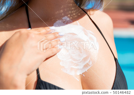 Woman in hat is applying sun cream  50146482