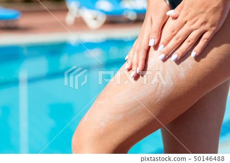 Woman in hat is applying sun cream  50146488