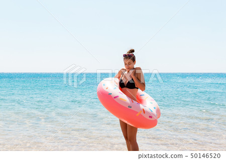 Woman relaxing with inflatable ring on the beach. 50146520