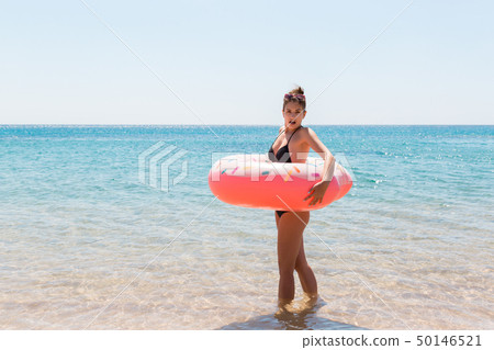 Woman relaxing with inflatable ring on the beach. 50146521