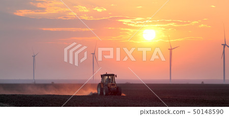 Tractor in field and windmillsin sunrise or sunset 50148590