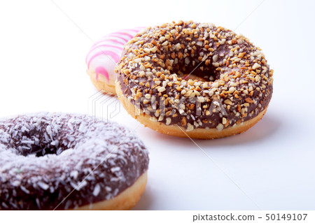 Assorted doughnuts in the glaze, colorful sprinkles and nuts on a white background. 50149107