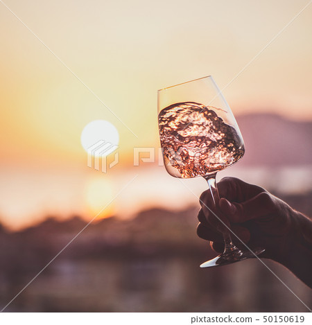 Glass of rose wine in hand with sunset at 50150619