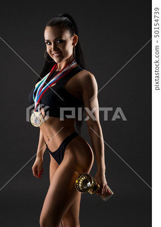 Fitness model with winner's cup and medal shot 50154739