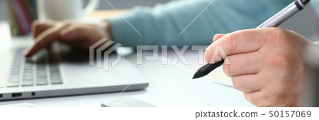 A young designer holds a pen from a tablet in his 50157069