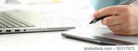 A young designer holds a pen from a tablet in his 50157072