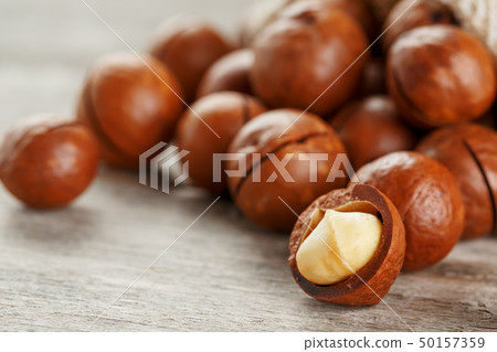 Macadamia nut on a wooden table in a bag, closeup, 50157359