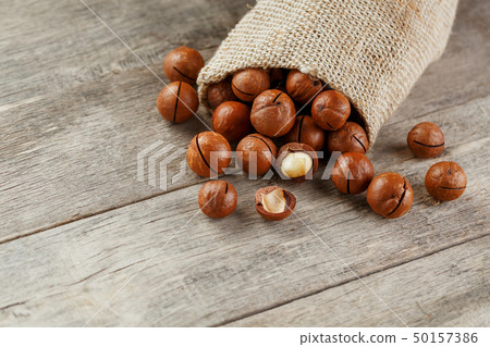 Macadamia nut on a wooden table in a bag, closeup, 50157386