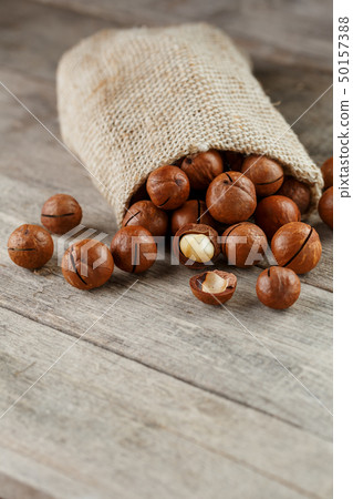 Macadamia nut on a wooden table in a bag, closeup, 50157388