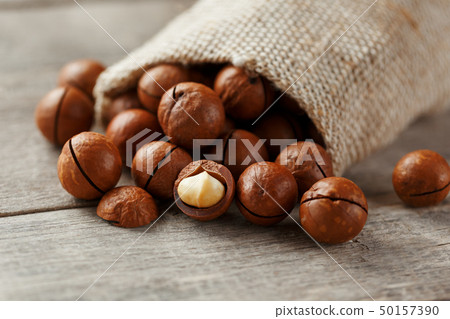 Macadamia nut on a wooden table in a bag, closeup, 50157390