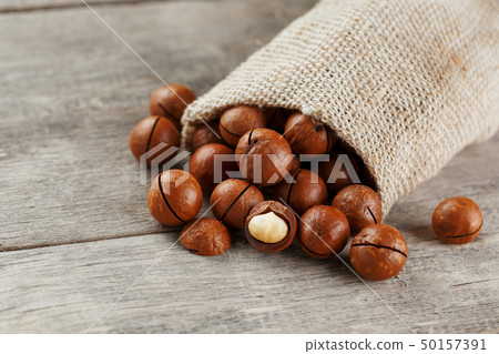 Macadamia nut on a wooden table in a bag, closeup, 50157391