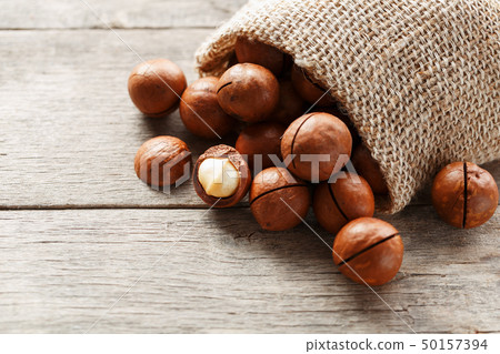 Macadamia nut on a wooden table in a bag, closeup, 50157394