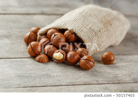 Macadamia nut on a wooden table in a bag, closeup, 50157403