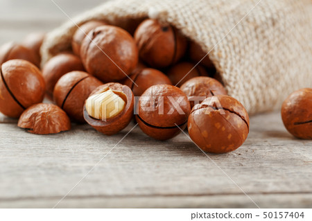 Macadamia nut on a wooden table in a bag, closeup, 50157404