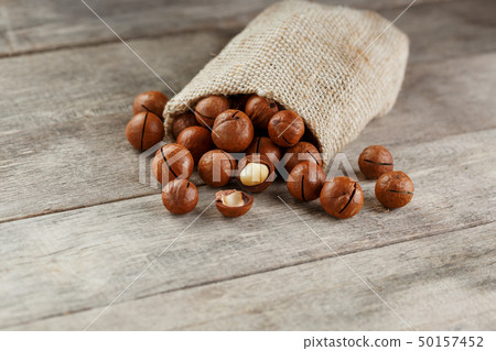 Macadamia nut on a wooden table in a bag, closeup, 50157452