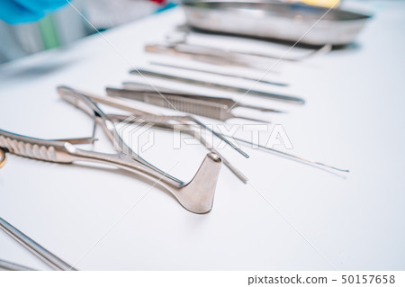 Several surgical instruments lie on a white table Several surgical instruments lie on a white table 50157658