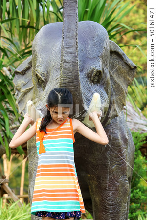 Asian girl enjoying with elephant statue in the Asian girl enjoying with elephant statue in the 50161471