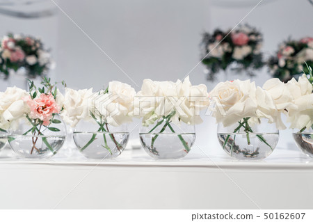 Small flower arrangements in ball glass vases. The table of the newlyweds. Interior of restaurant 50162607