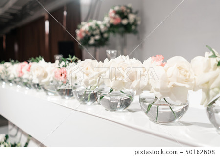 Small flower arrangements in ball glass vases. The table of the newlyweds. Interior of restaurant Small flower arrangements in ball glass vases. The table of the newlyweds. Interior of restaurant 50162608