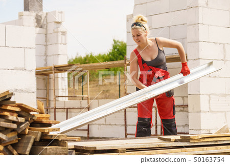 Woman carrying gutter on construction site 50163754