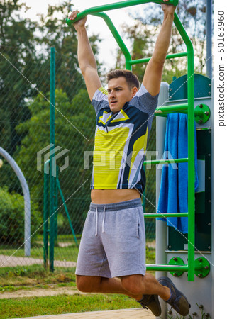 Man doing pull ups in outdoor gym Man doing pull ups in outdoor gym 50163960