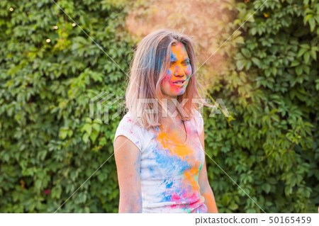 Holi festival, holidays and people concept - young woman having a fun at the festival of holi Holi festival, holidays and people concept - young woman having a fun at the festival of holi 50165459