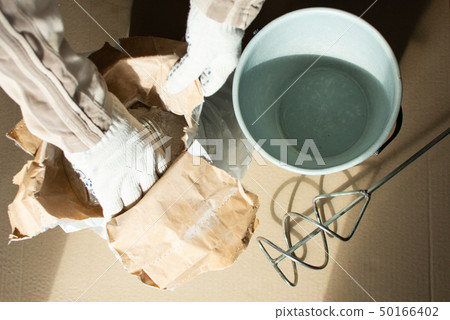 Man builder prepares a mixture for putty Man builder prepares a mixture for putty 50166402