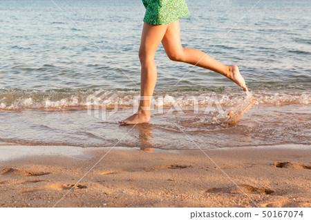 Leg of woman running on beach with water 50167074