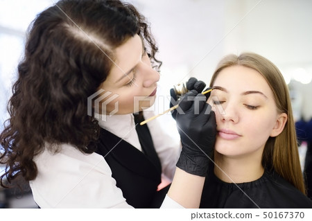 Cosmetologist painting eyebrows by brush. Cosmetologist painting eyebrows by brush. 50167370