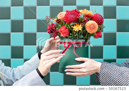 Young woman receiving beautiful peony flowers from delivery woman. Young woman receiving beautiful peony flowers from delivery woman. 50167523